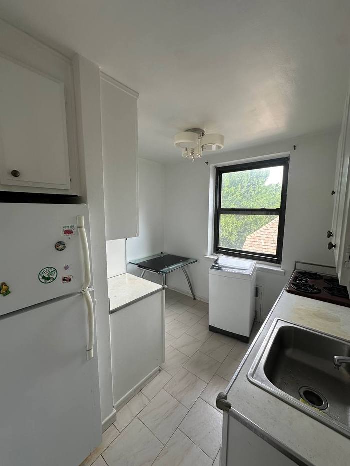 The Brooklyn kitchen before: old white cabinets, freestanding fridge and worn counters